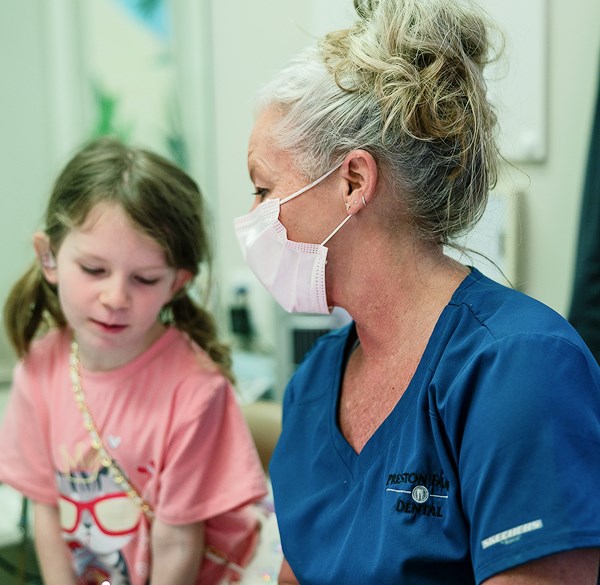 Dentist assisting child with first dental visit