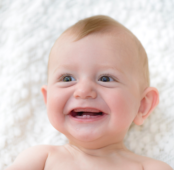 Smiling infant with emerging teeth